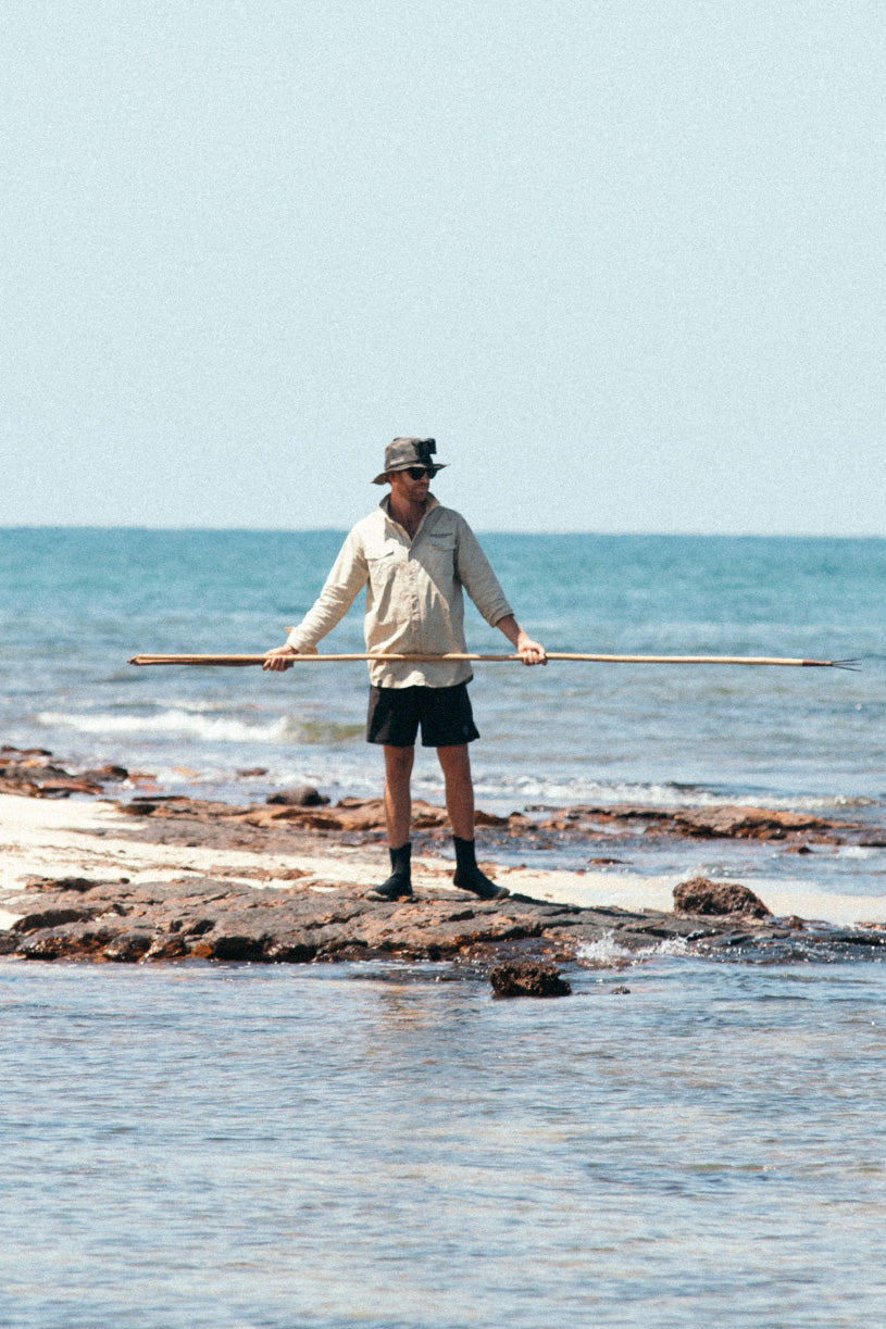 strick with a traditional fishing spear in his back 2 basics light weight fishing shirt on a tropical island