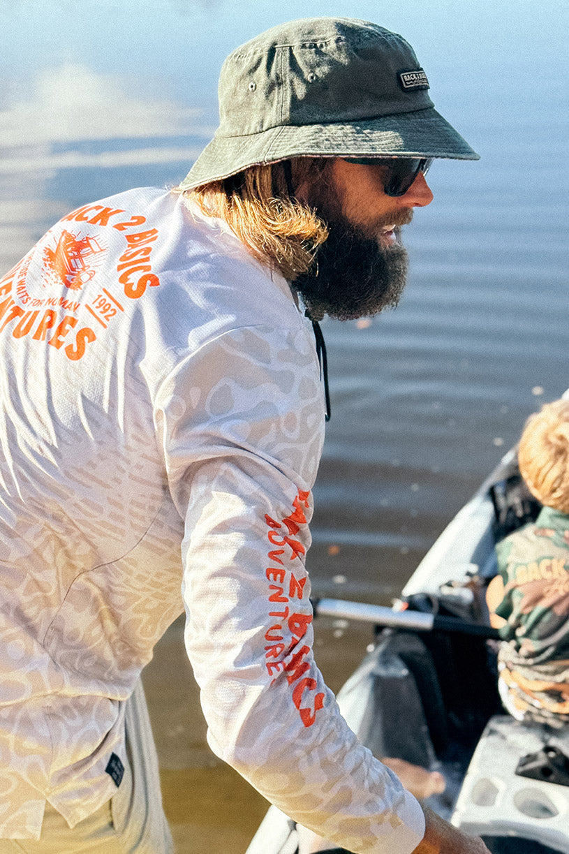 man wearing a B2B Adventure Fishing Jersey in beige carrying a fishing kayak