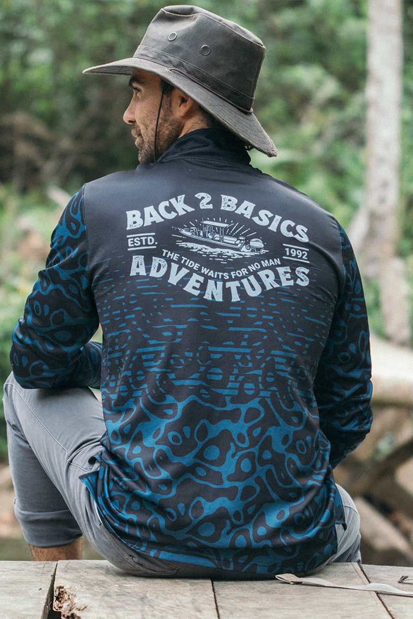 aaron in his back 2 basics adventures fishing jersey sitting on a pier while waiitng for a fishing boat