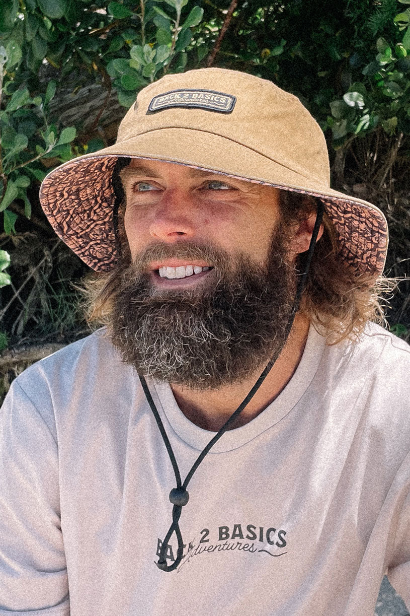 wearing a b2b grab life bucket hat in rust colour down at the beach