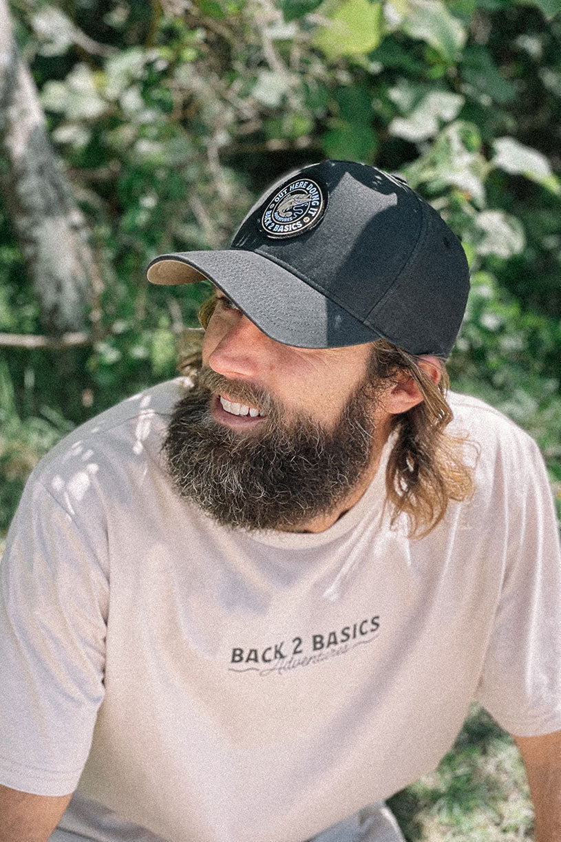 a black structured hat with picture of a barramundi and text saying out here doing it in black